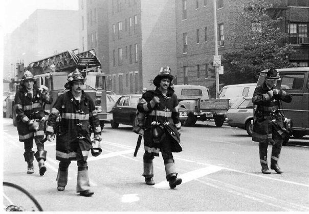 Firefighters walk down the street in full bunker gear