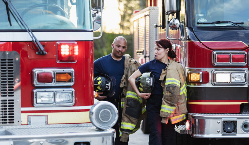 two firefighters carry their turnout gear to be cleaned