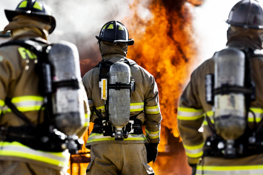 firefighters in full PPE prepare to extinguish an open fire