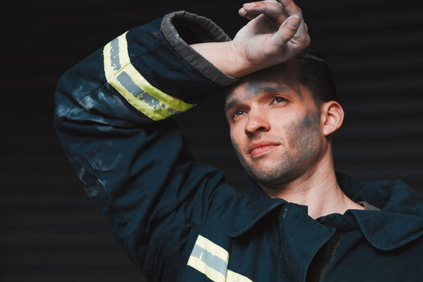 A firefighter wipes off sweat after responding to a call